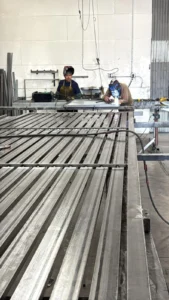 Two welders working on a large, flat metal structure.