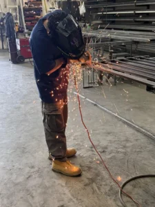 A worker using a grinder on metal with bright sparks flying.